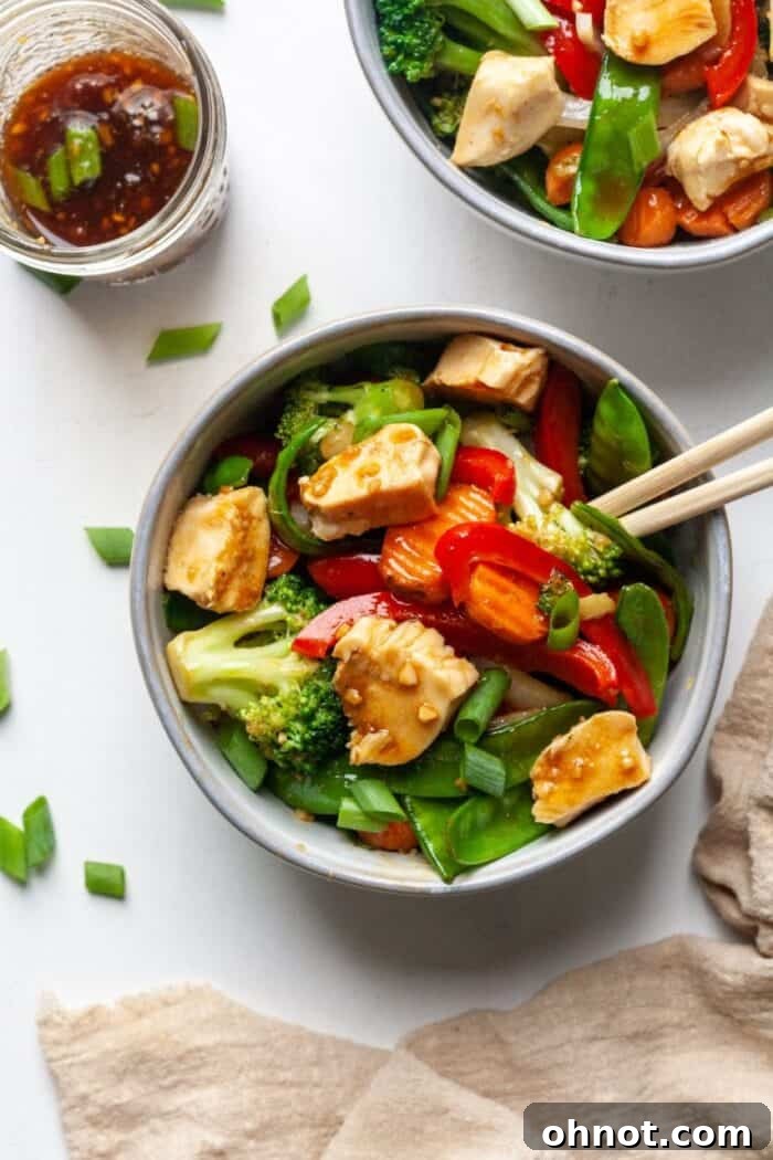 Chicken and veggie stir fry in bowl with chopsticks