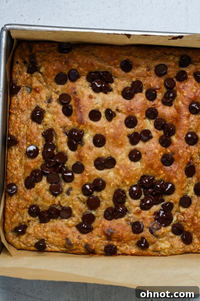 Freshly baked banana bread bars in a parchment-lined square pan, cooling on a wire rack.