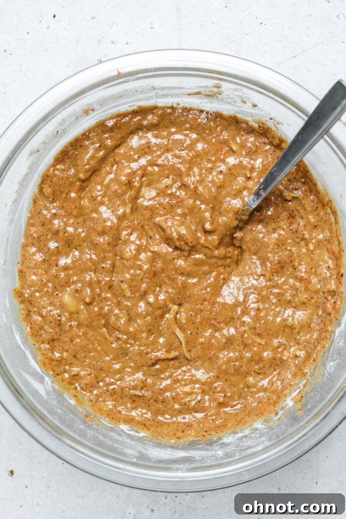 Spiced bread batter with flecks of carrot and coconut, mixed to perfection in a bowl, ready for baking.