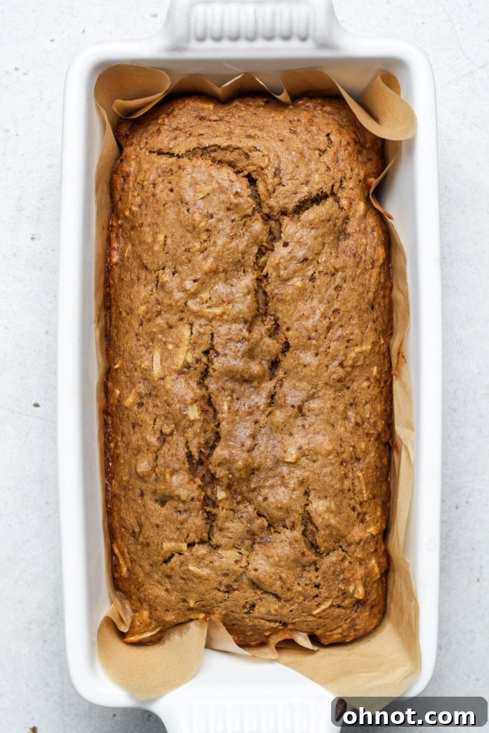 Freshly baked carrot cake banana bread, golden brown and risen, cooling in its loaf pan after coming out of the oven.