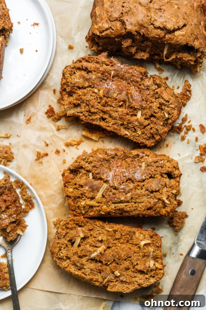 A slice of carrot coconut bread on a plate, showcasing its fluffy texture and delightful specks of carrot and coconut flakes, ready to be enjoyed.