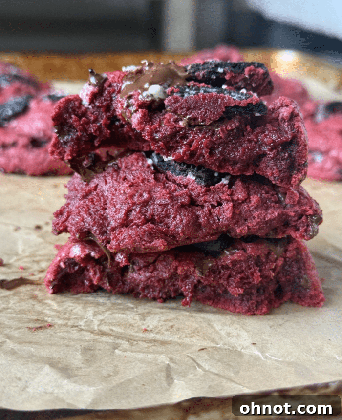 A stack of gooey, perfectly baked red velvet cookies, showing their soft centers.