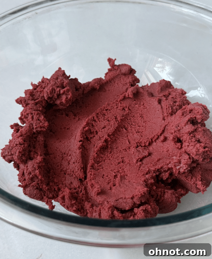A bowl of rich, dark red cookie dough, perfectly mixed.