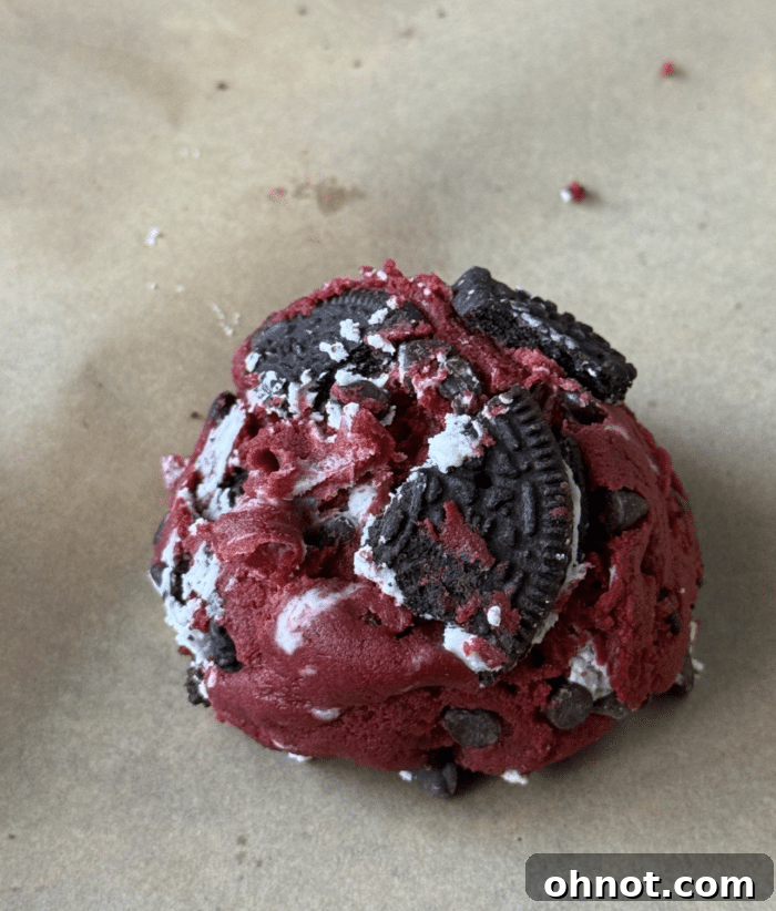 Raw red velvet cookie dough scoops on a parchment-lined baking sheet.
