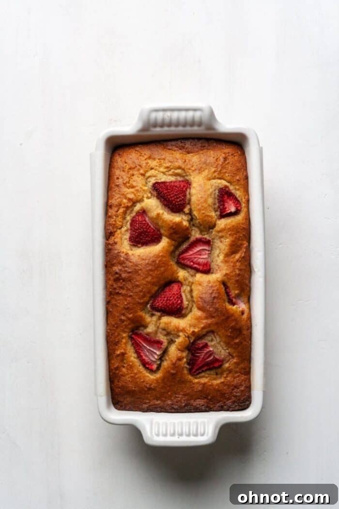 A freshly baked loaf of Paleo strawberry banana bread on a white cooling rack.