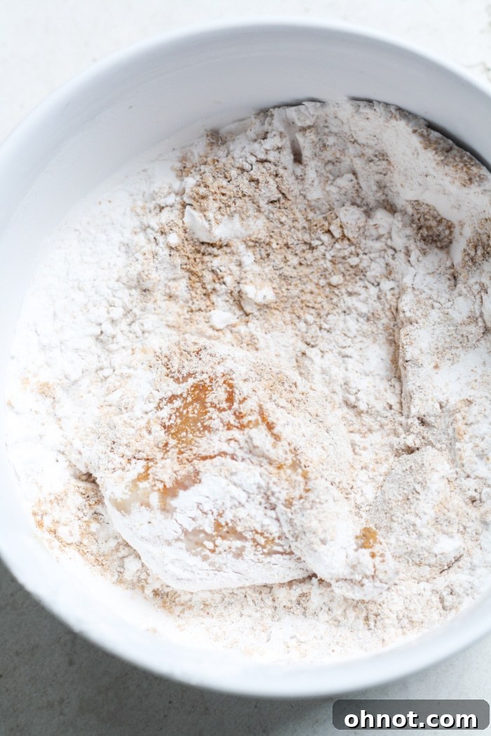 A piece of chicken fully coated in the gluten-free breading mixture, ready for cooking.