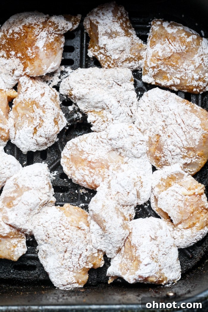 Coated chicken nuggets neatly arranged in an air fryer basket, ready to be cooked.