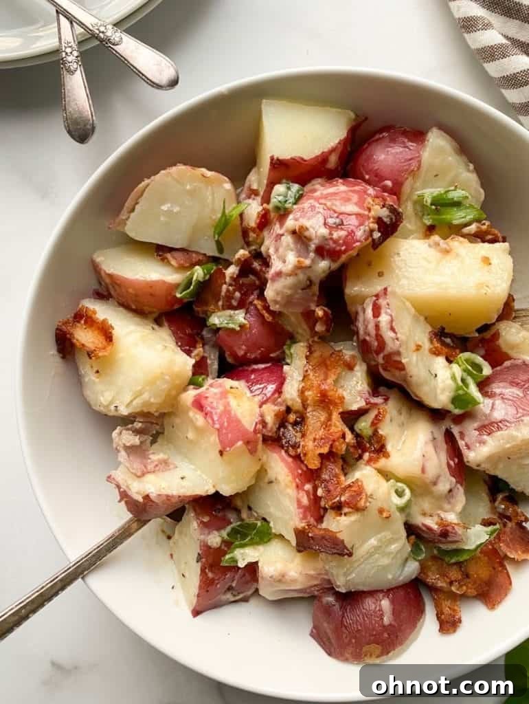 A crisp white bowl filled with the dairy-free potato salad, highlighting its clean and wholesome appearance, garnished with fresh herbs.