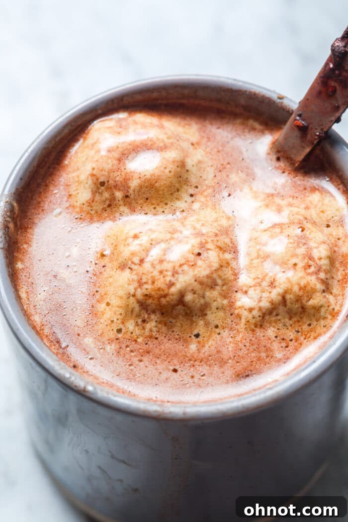 A perfectly prepared mug of healthy hot chocolate, generously topped with fluffy marshmallows, resting on a wooden tray, suggesting a cozy and indulgent moment.