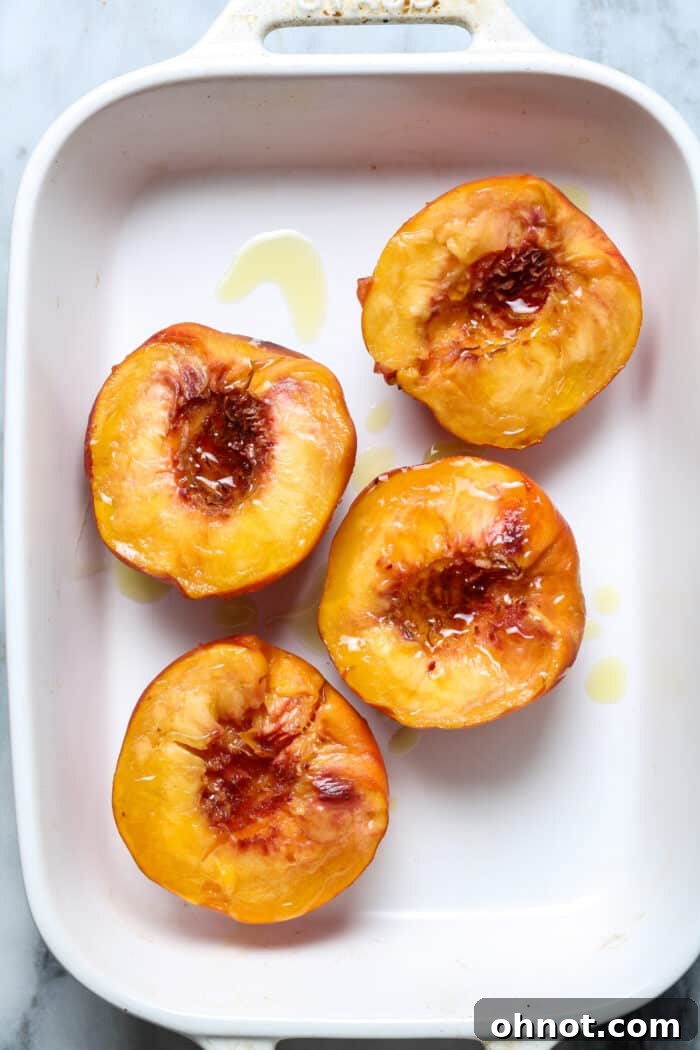 Baking dish with yellow fruit halves drizzled with olive oil, ready for the oven.