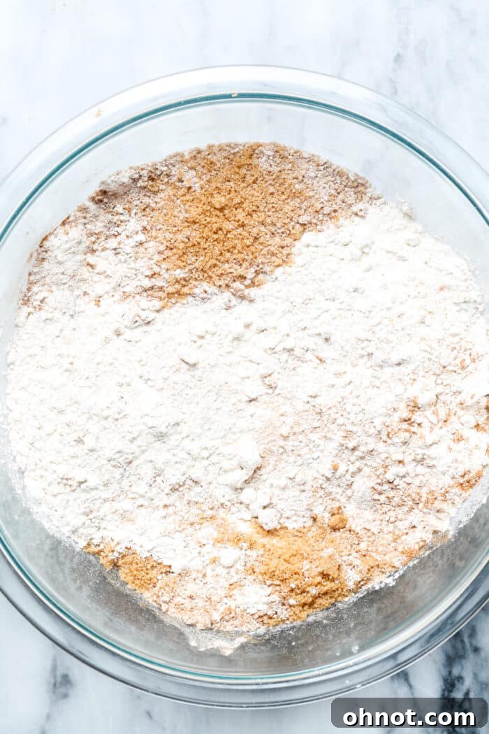 A glass bowl filled with dry ingredients for pumpkin cake.