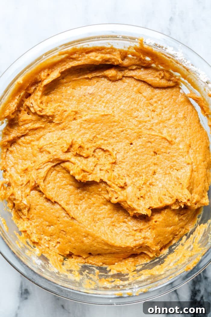 Vibrant orange cake batter in a glass mixing bowl.
