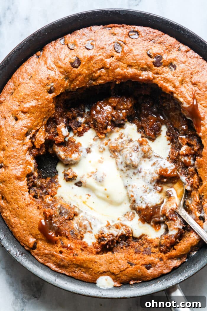 Close-up of a bite taken from a pumpkin skillet cookie, showing gooey chocolate chips.