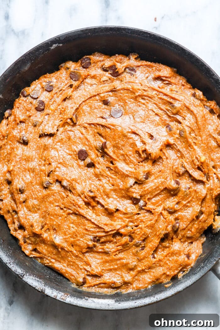 Pumpkin cookie dough mixed with chocolate chips in a skillet.