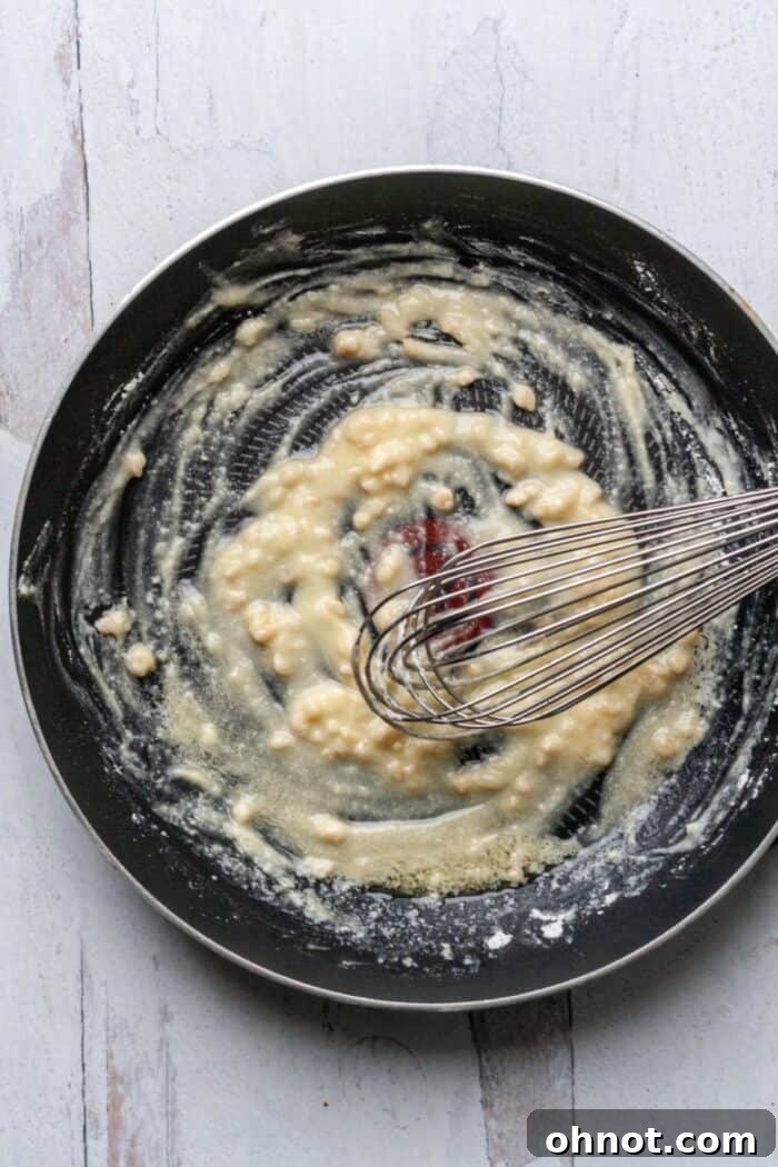 The initial stage of making Whole30 Scalloped Potatoes, showing melted ghee and almond oil with tapioca flour being whisked in a skillet.