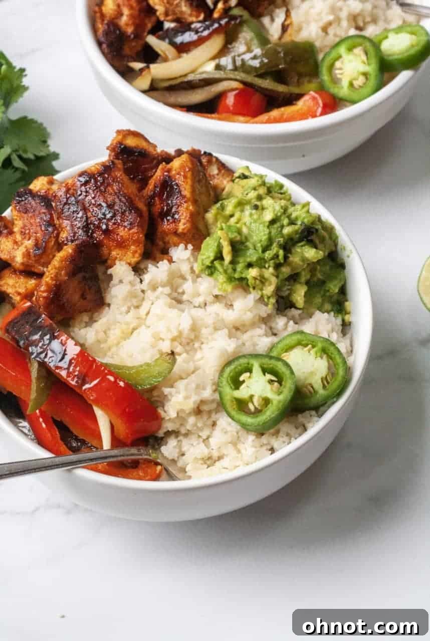 Delicious chicken fajita bowl with seasoned chicken, colorful peppers, onions, and guacamole over cauliflower rice, perfect for Whole30 and Paleo diets.