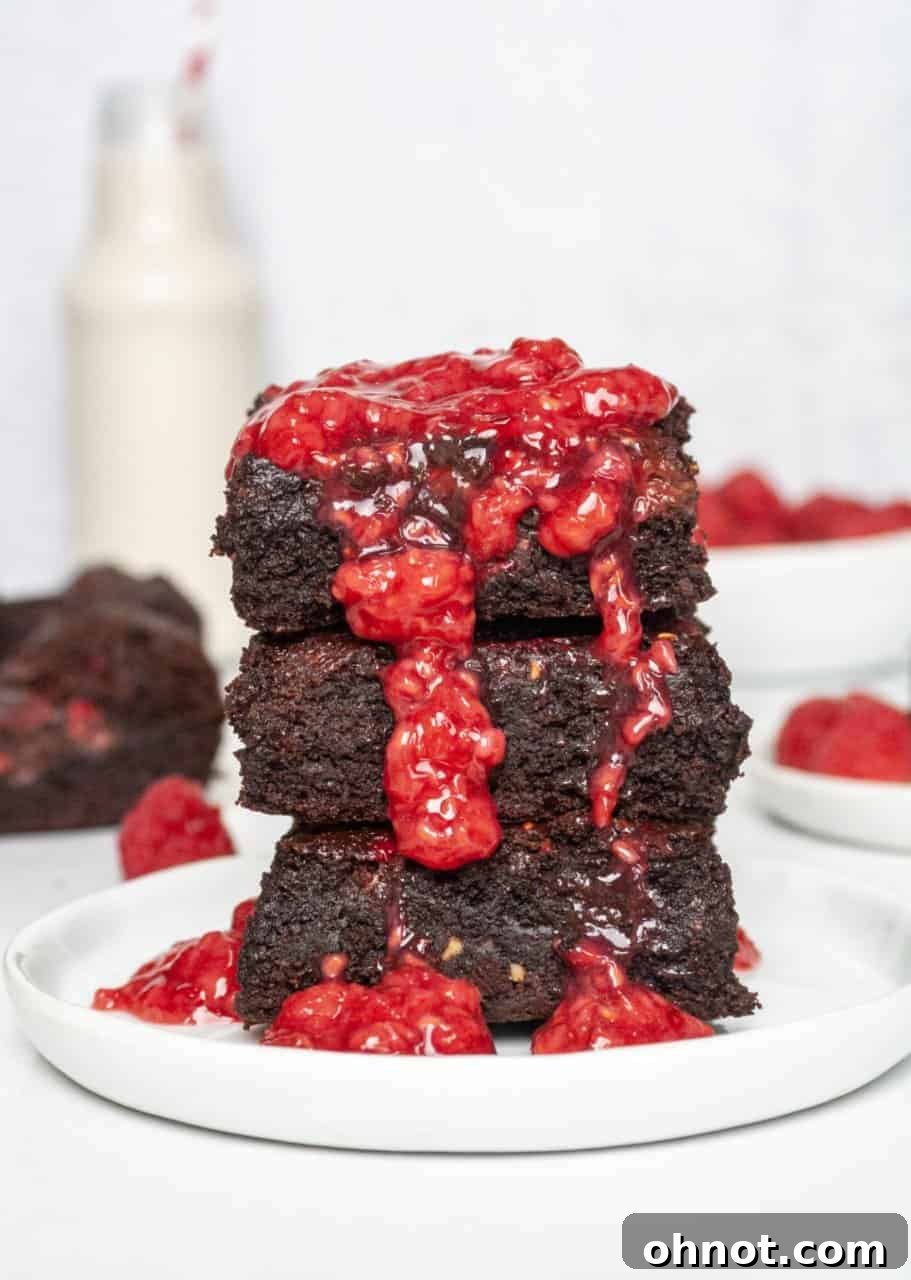 A tray of freshly baked, fudgy grain-free raspberry brownies cooling on a wire rack, showing off their rich chocolate and vibrant red swirls.