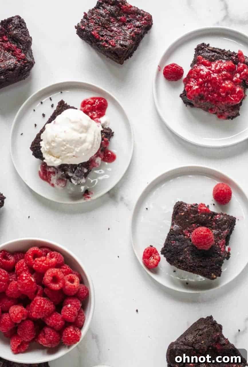 Close-up of brownie batter in a baking pan with vibrant red raspberry jam being swirled in with a knife before baking.
