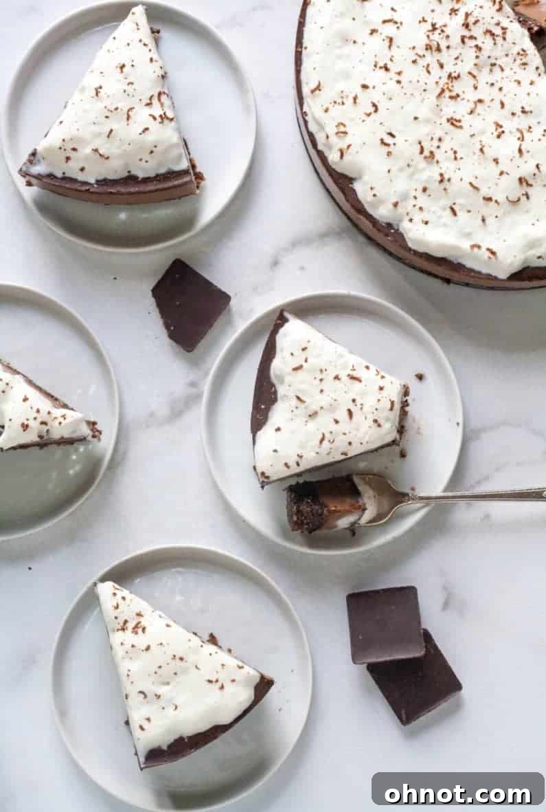 A slice of triple chocolate no-bake vegan cheesecake garnished with a dollop of coconut whipped cream and fresh raspberries.