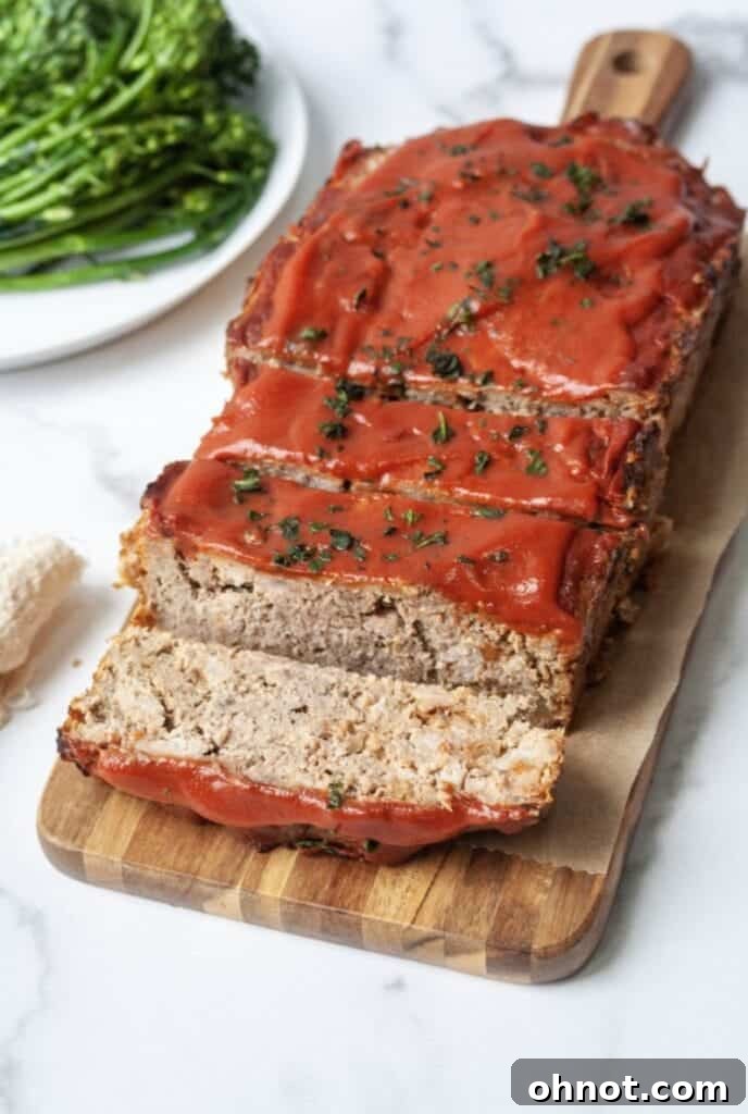 Almond flour meatloaf on cutting board with fresh herbs