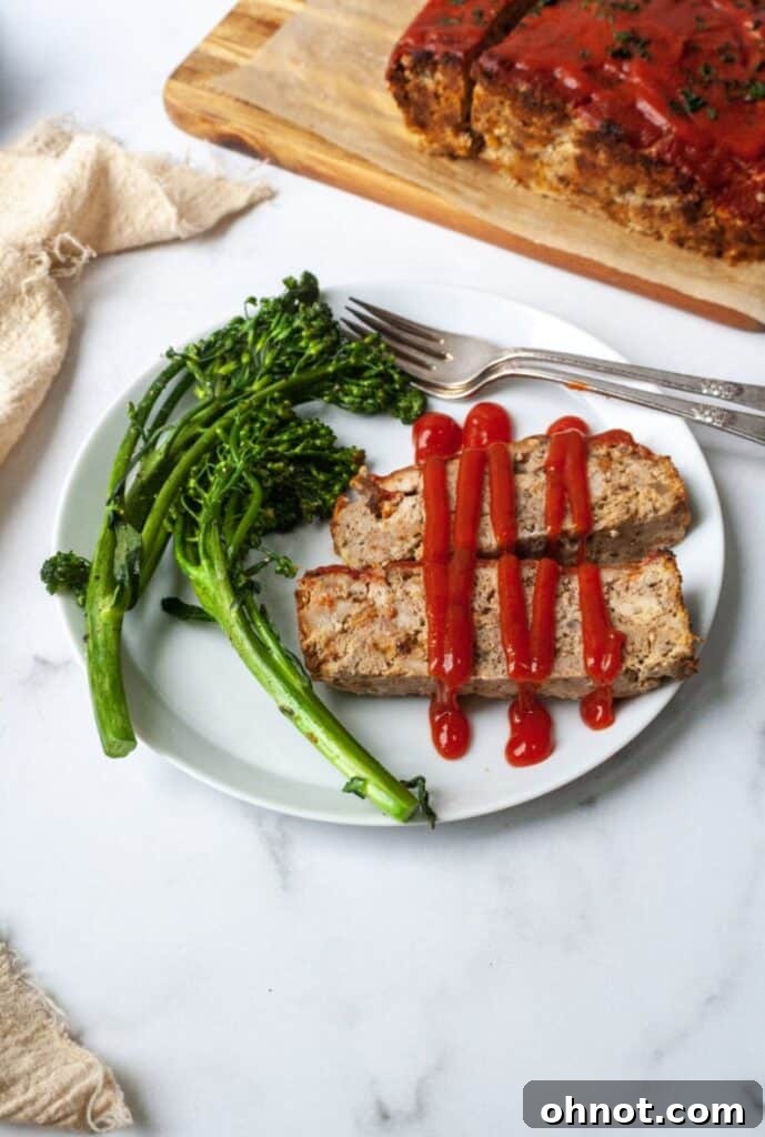 A slice of meatloaf with ketchup and a fork