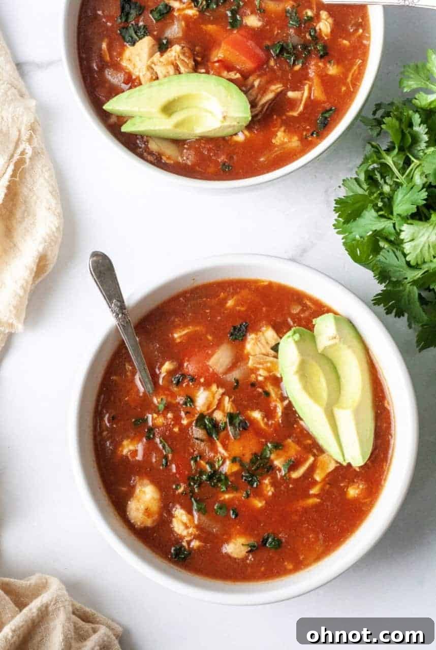 Delicious Whole30 Chicken Tortilla Soup in a bowl with fresh avocado and cilantro garnishes.