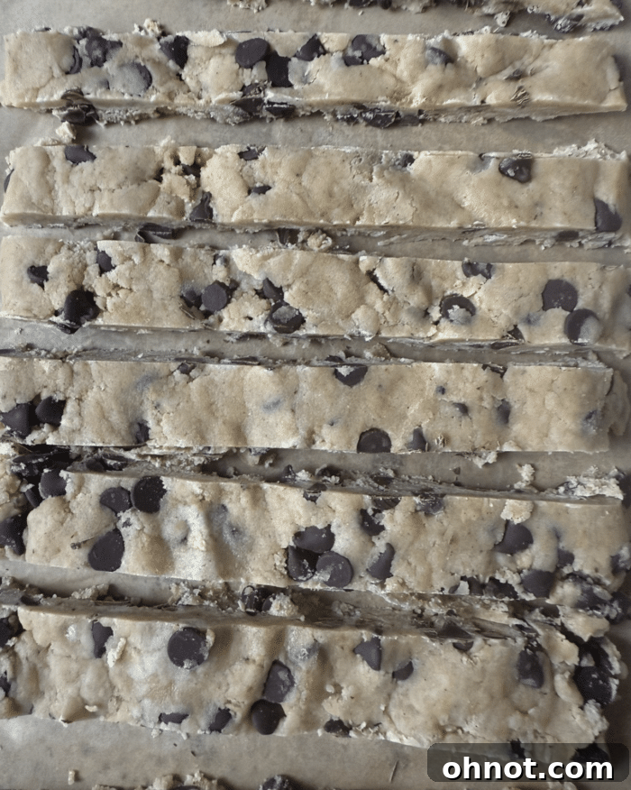 Several rows of precisely cut cookie dough strips on a baking sheet, ready for baking.