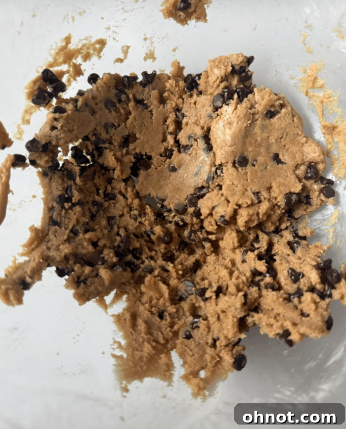 Cookie dough with mini chocolate chips mixed in, showcasing its thick consistency, ready for scooping.