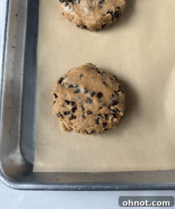 Raw protein cookie dough balls neatly arranged on a parchment-lined baking sheet before baking.