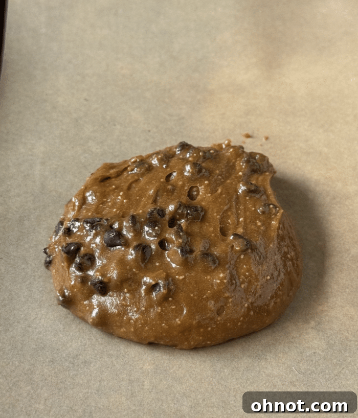 Scooped gooey peanut butter protein cookie dough balls on a baking sheet.