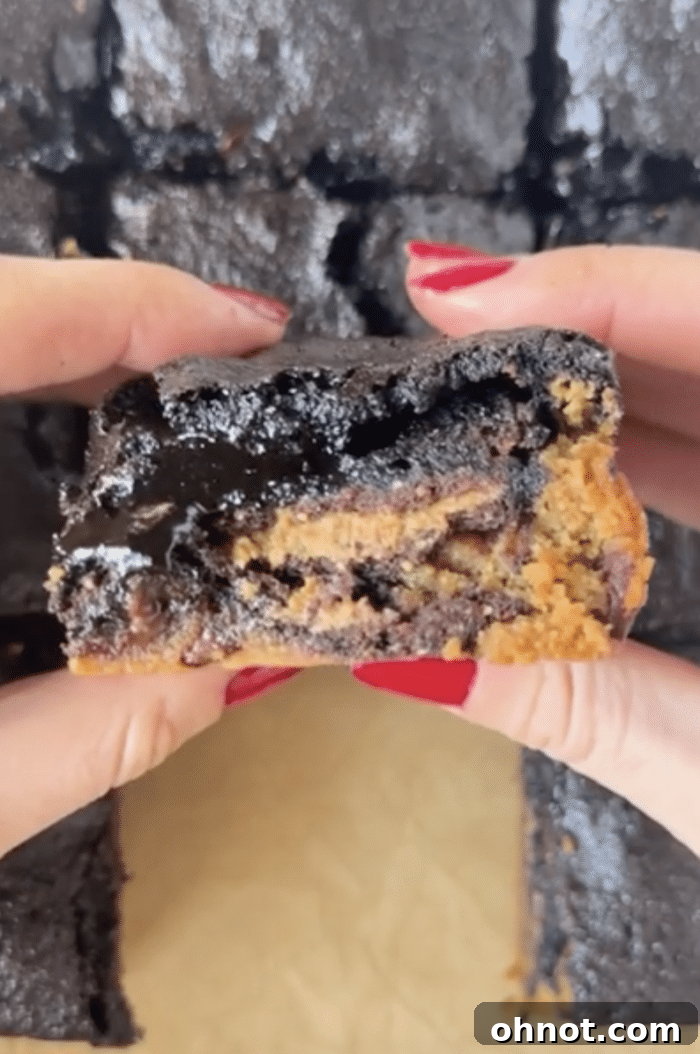 Hands holding a freshly cut Stuffed Brookie, showing the layered interior.