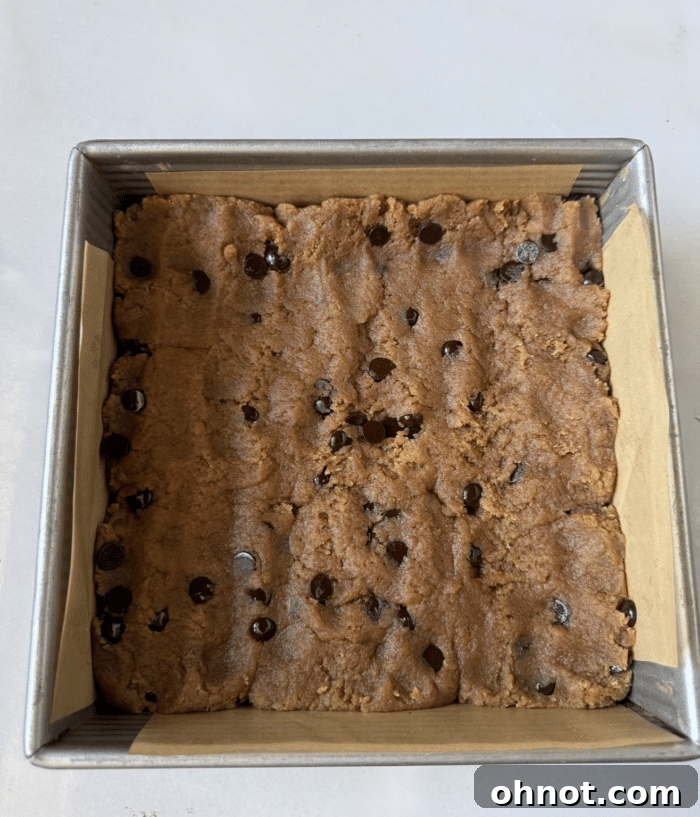 Square baking pan with an even layer of cookie dough pressed into it.