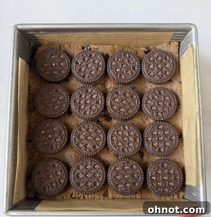 Sandwich cookies arranged neatly on top of the cookie dough layer in the baking pan.