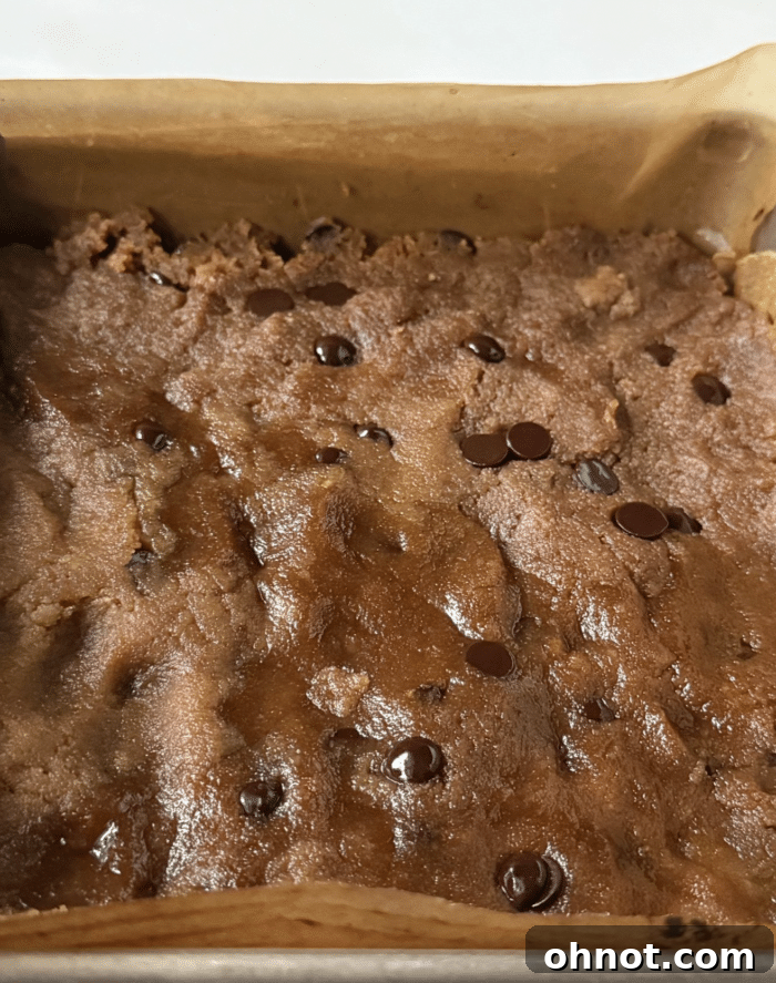 Cookie dough pressed into a square baking pan.