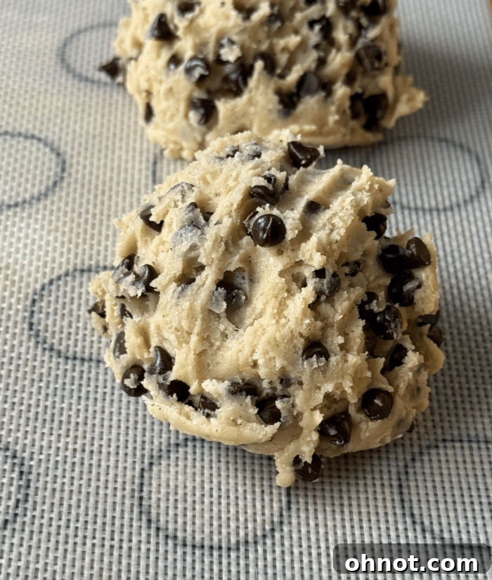 Perfectly scooped, uniform balls of cottage cheese cookie dough arranged neatly on a parchment-lined baking sheet, ready for the oven.