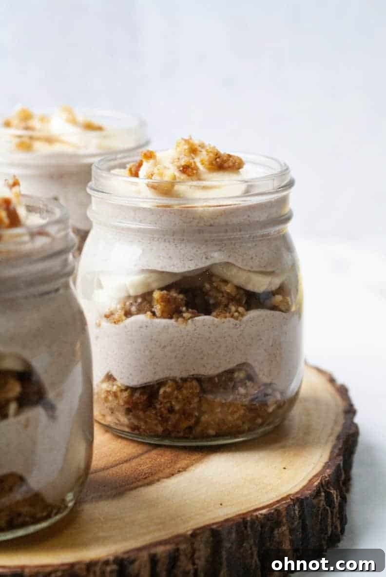 Close-up of a beautifully layered banana cream pie jar with a healthy crust and fresh banana slices, ready to be enjoyed.