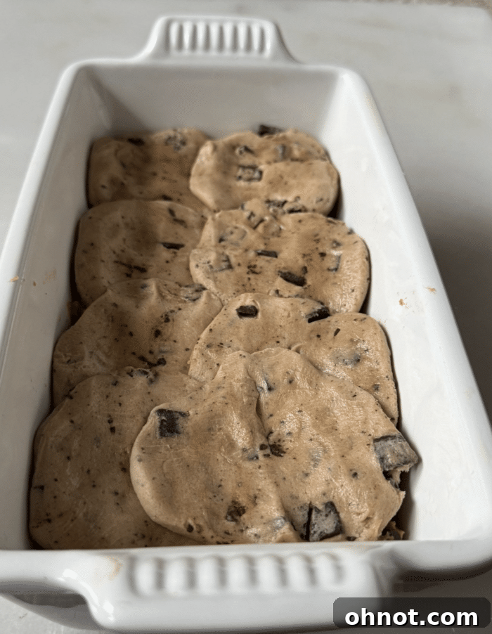 A layer of edible chocolate chip cookie dough balls gently placed over the first half of bread batter in a loaf pan, before adding the top layer.
