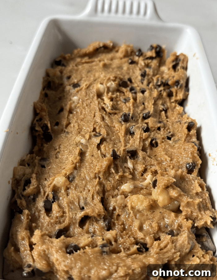 Unbaked peanut butter banana bread loaf with the cookie dough layer fully covered, smoothed, and ready for the oven.