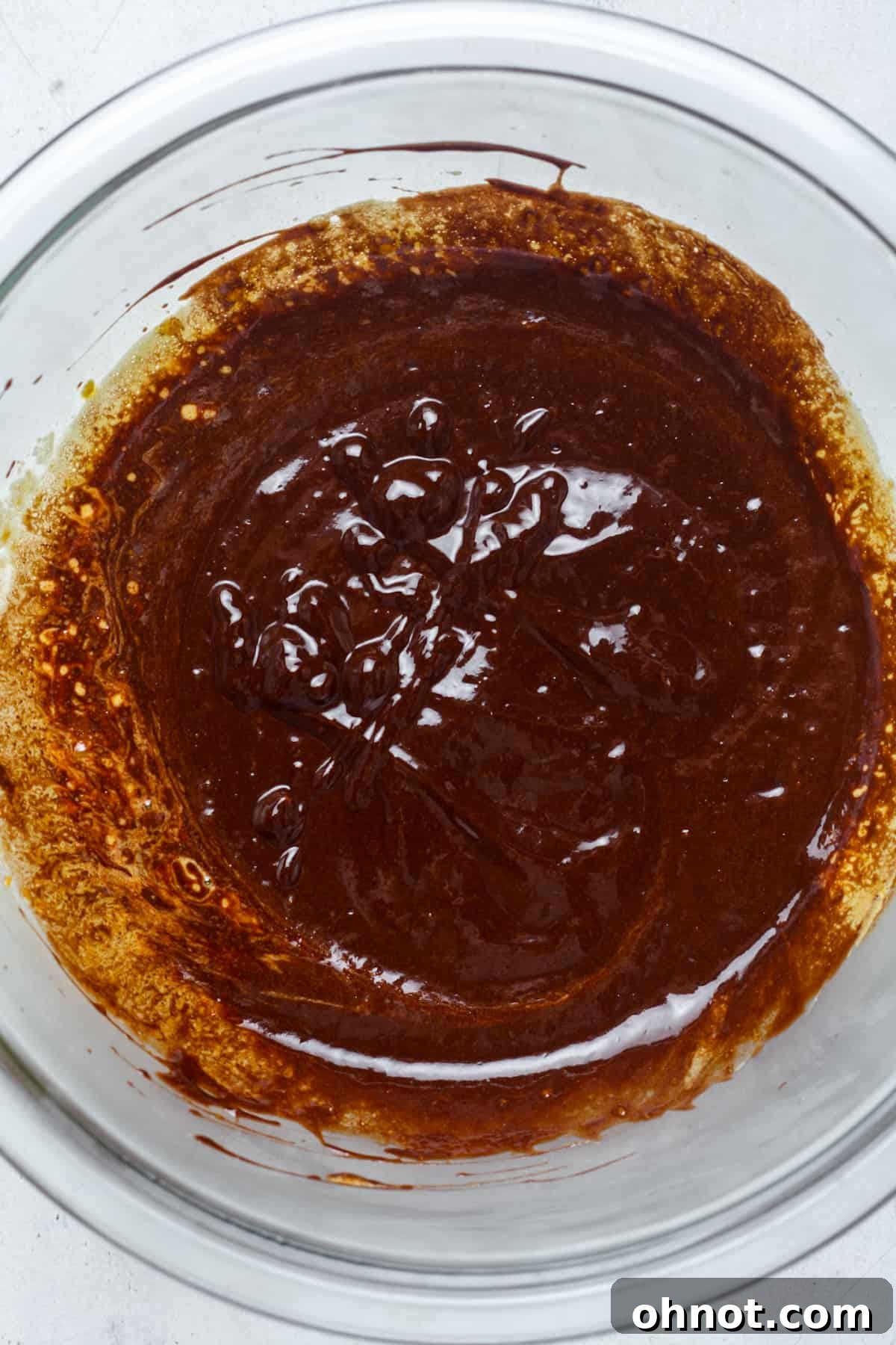 Thick, rich chocolate batter in a glass mixing bowl, ready for dry ingredients.
