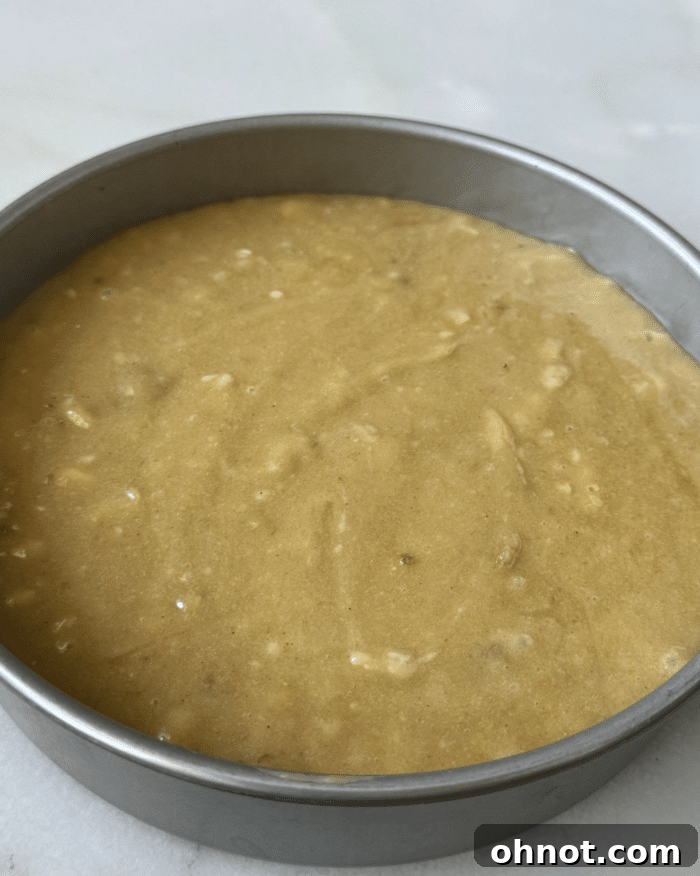Cake batter poured over the caramelized bananas in a circular baking pan.