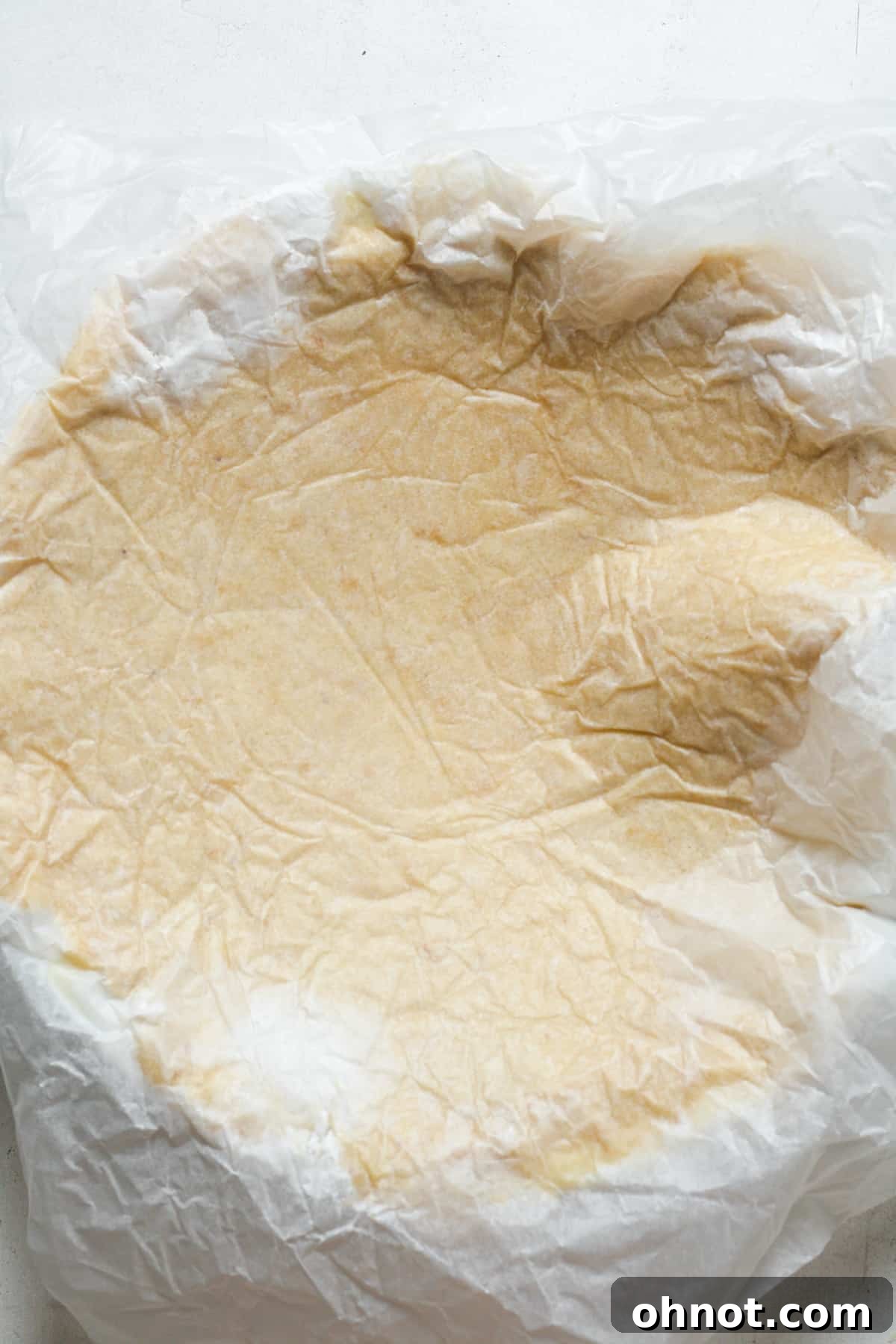 The Paleo pie crust successfully inverted into the pie dish, with the parchment paper still covering the top.