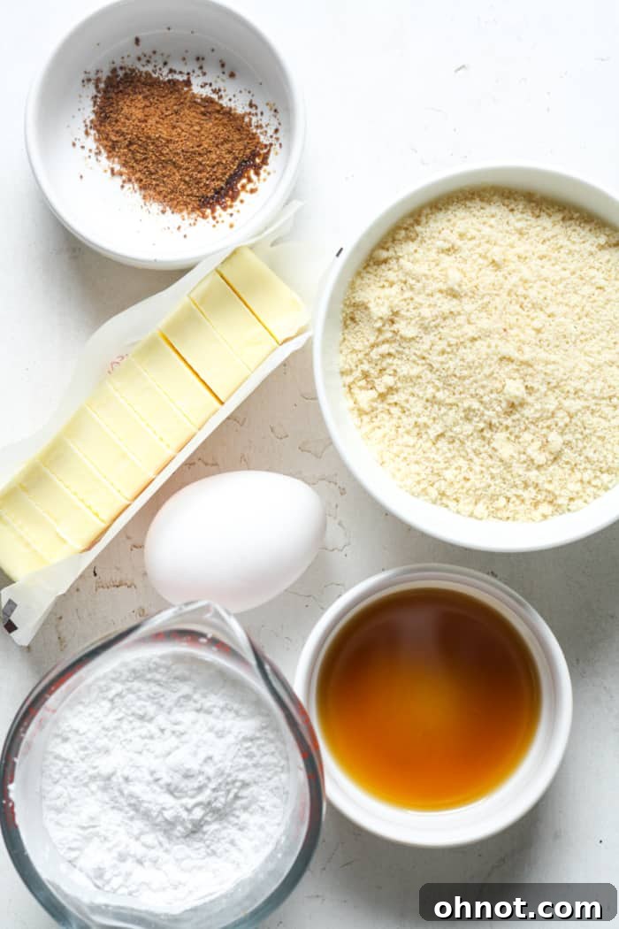Key ingredients for Paleo pie crust: blanched almond flour, maple syrup, and a fresh egg, laid out on a clean surface.