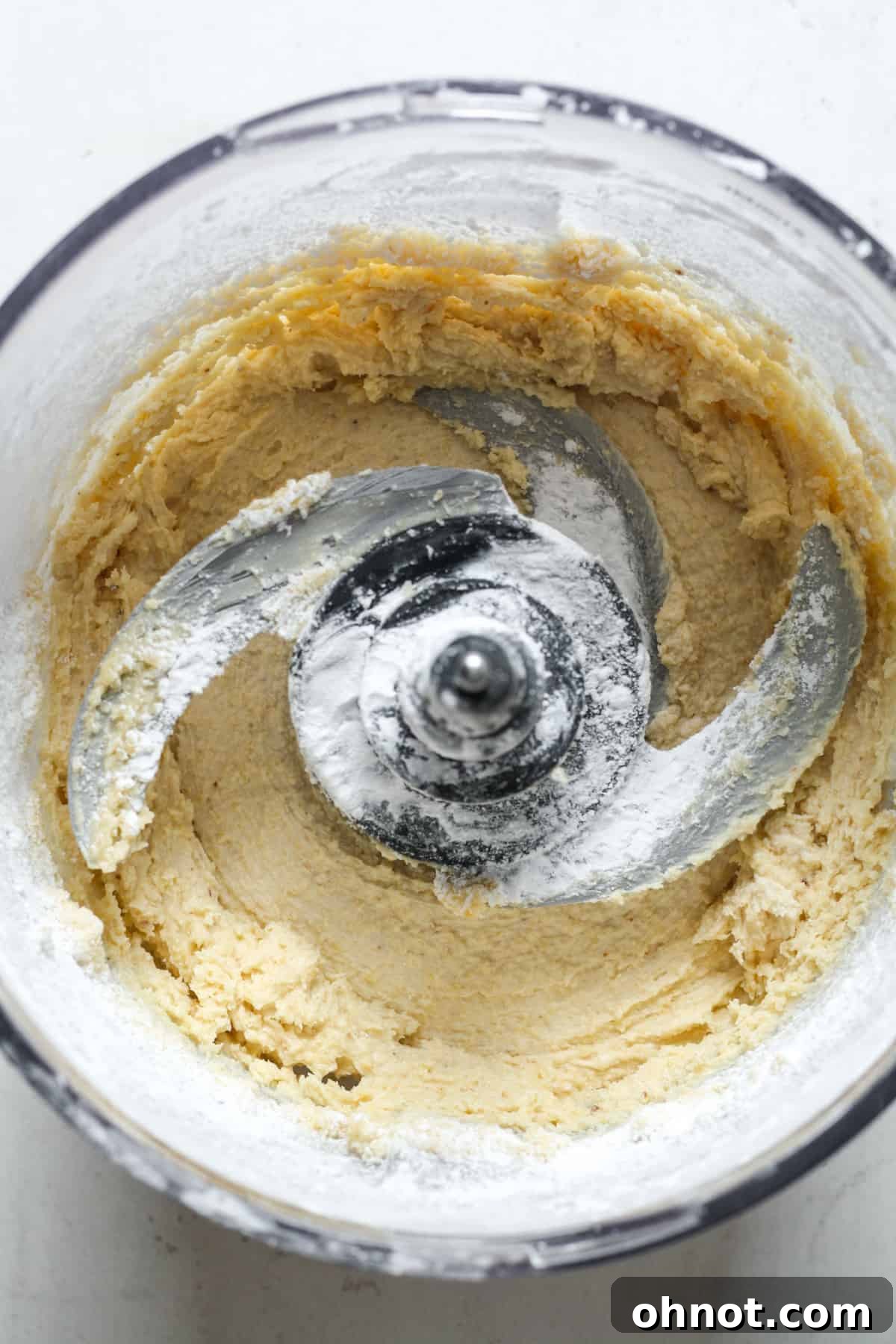The dough mixture achieving a crumbly texture in the food processor after pulsing.