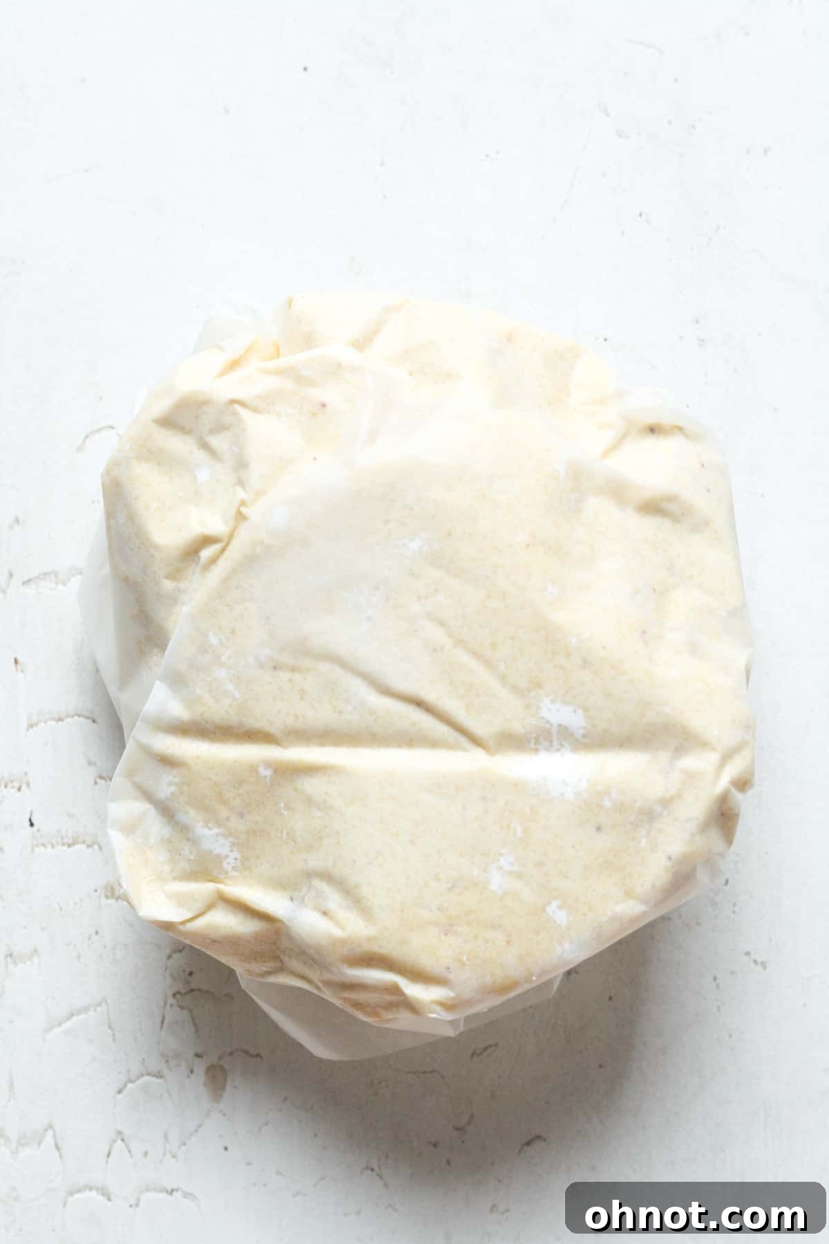 The prepared Paleo pie crust dough tightly wrapped in cling wrap, ready for chilling.