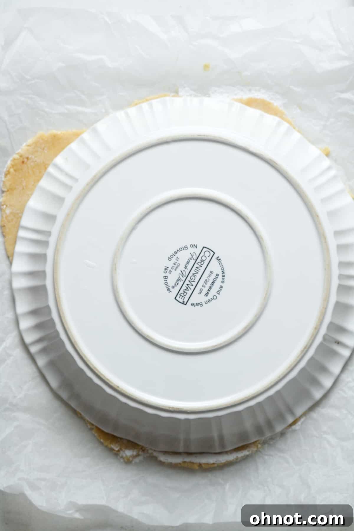 An empty pie dish placed upside down over the rolled-out Paleo pie crust.