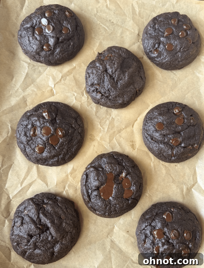 Freshly baked chocolate lava cookies cooling on a wire rack, with some having been broken open to reveal their rich, dark molten centers.