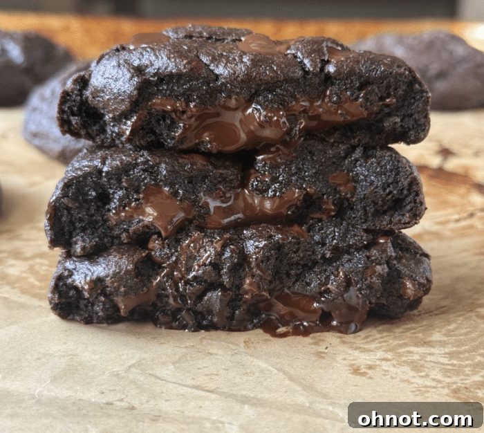 A stack of warm chocolate stuffed cookies, with one broken open to show the luscious, melted chocolate filling.