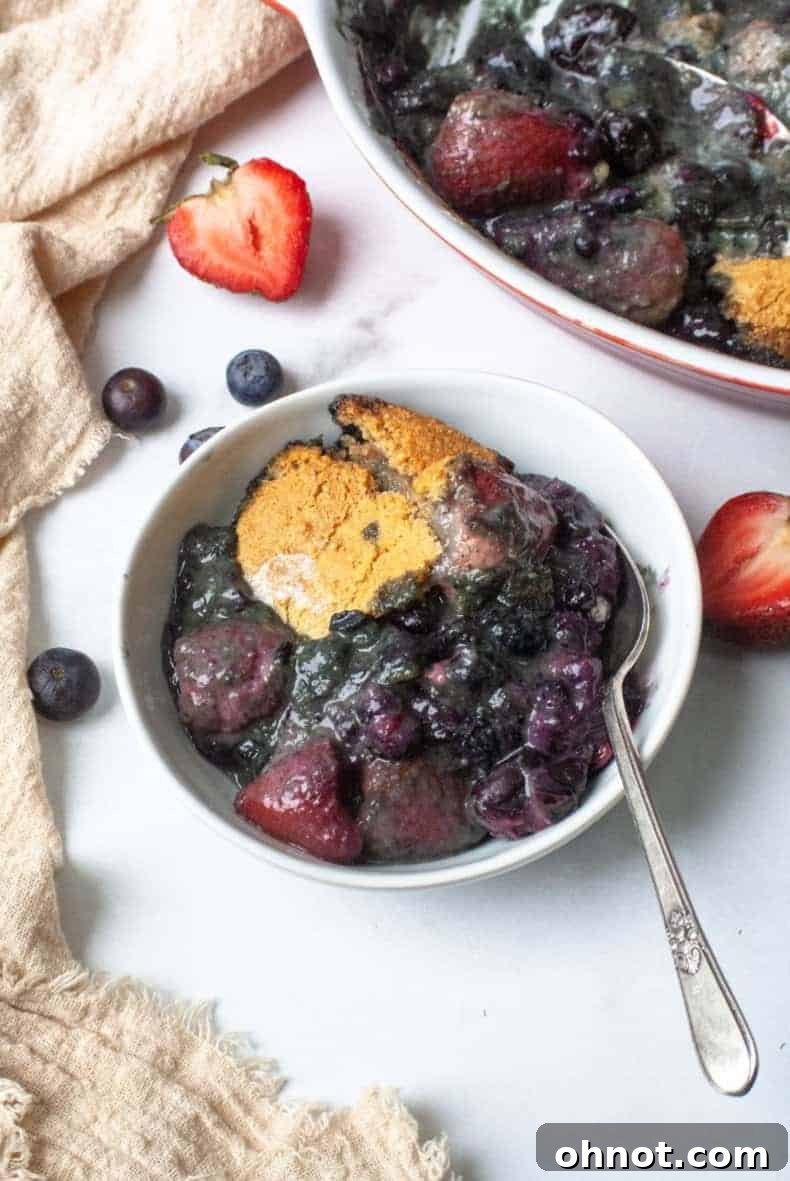 Homemade berry cobbler with a golden-brown, crumbly topping and vibrant berry filling, served warm in a baking dish
