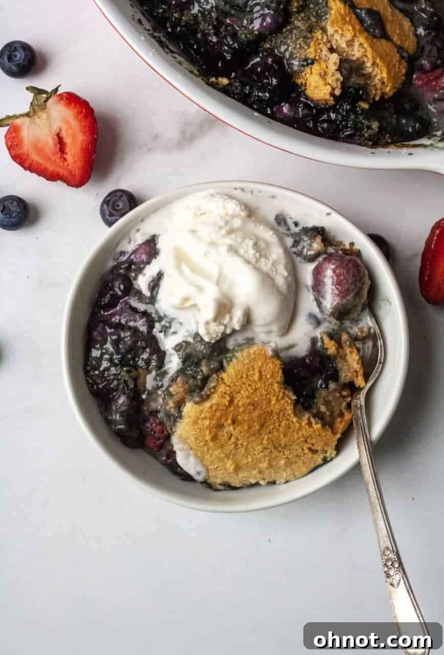 Close-up of a serving of vegan berry cobbler with a scoop of coconut milk ice cream, showcasing the rich textures