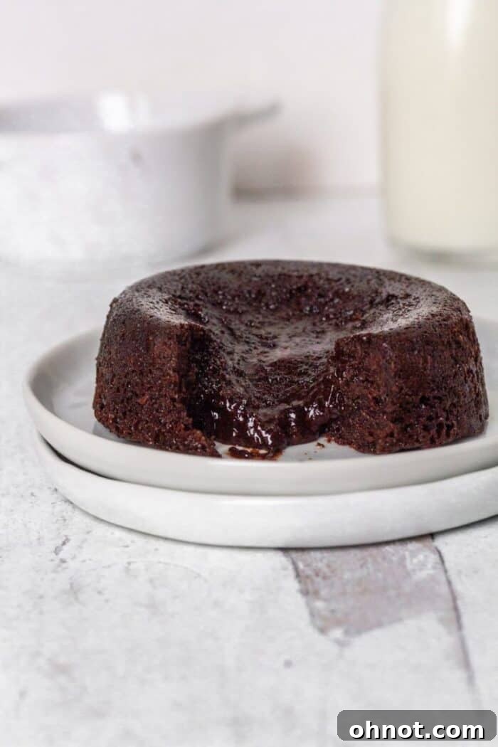 A single gluten free lava cake cut open, revealing its rich, gooey chocolate ganache center.